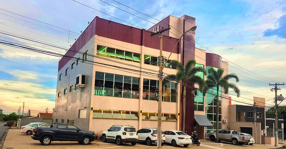 Fachada da 349 Fitness Experience no fim da tarde. Prédio de três andares com janelas em fita e carros estacionados na rua.