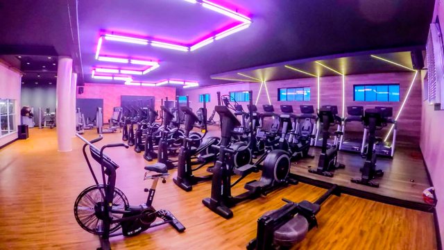 Sala de cardio com iluminação em neon violeta.