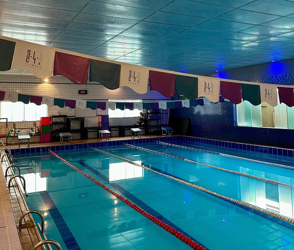 Piscina coberta da 349 com quatro raias, azulejo azul e bandeiras com o logotipo da 349 penduradas acima da água.